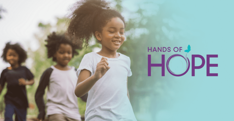 Children playing outside with Hands of Hope logo